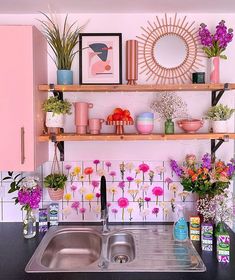 a kitchen with pink cabinets and shelves filled with flowers