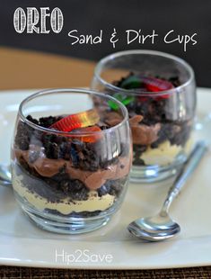 two glasses filled with dirt cups on top of a white plate next to spoons