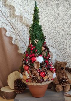 a potted christmas tree sitting on top of a table next to a teddy bear