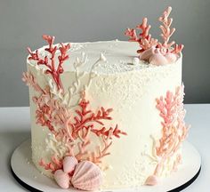 a white cake decorated with corals and seashells