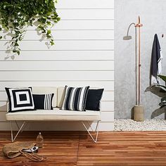 a white couch sitting on top of a wooden floor next to a potted plant