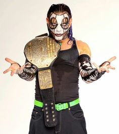 the wrestler is posing with his arms spread out to show off his muscles and face paint