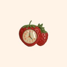 a red clock with two strawberries attached to it's sides on a white background