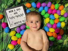 a baby laying on top of candy eggs with a sign that says mom & dad are egg - shaped