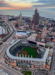 an aerial view of a baseball stadium with the city skyline in the background at sunset