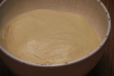 a white bowl filled with batter on top of a wooden table