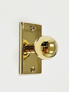 an image of a door handle on a white wall with gold knobs and a reflection in the ball