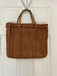 a crocheted bag hanging on the front door with two hooks attached to it