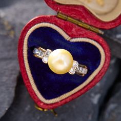 This beautiful ring is centered with a slightly cream colored round pearl.  Each shoulder is accented with two semi bezel set round diamonds and four channel set princess cut diamonds.  It is crafted in 14k yellow gold and is currently a size 4.75. Classic Diamond Pearl Ring Hallmarked, Classic Pearl Ring With Diamond Center Stone, Classic Pearl Ring With Diamond, Yellow Gold Pearl Jewelry With Brilliant Cut, Yellow Gold Pearl Jewelry, Classic Pearl Ring With Single Diamond For Anniversary, Anniversary Yellow Gold Pearl Ring With Diamond, Heirloom Pearl Ring With Diamond, Hallmarked, Heirloom Gold Pearl Ring With Center Stone