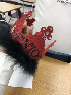 a person wearing a red crown with black feathers on their head and the words bravo written on it