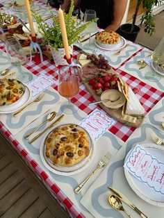 a table topped with lots of plates and food covered in toppings on top of red and white checkered cloth