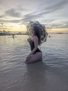 a woman sitting in the water with an umbrella