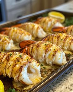 lobsters and shrimp on a baking sheet with lemon wedges