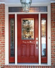 a red front door with two sidelights and glass panels on the top, along with brick steps leading up to it