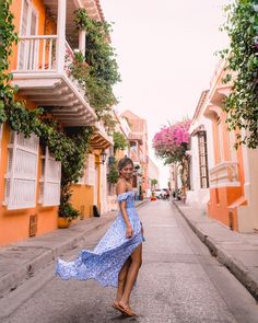 a woman in a blue dress is walking down the street with her arms around her waist