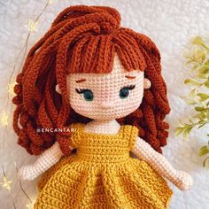 a crocheted doll with long red hair wearing a yellow dress and green eyes