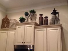 the kitchen cabinets are all white with pots and vases on top of each cabinet