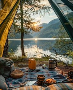 a tent is set up on the ground with food and coffee in front of it