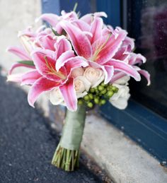 a bouquet of pink and white flowers sitting in front of a window