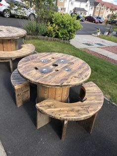 three wooden tables and benches on the side of a road in front of some houses