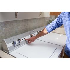 a man is pointing at an appliance on top of a washer and dryer