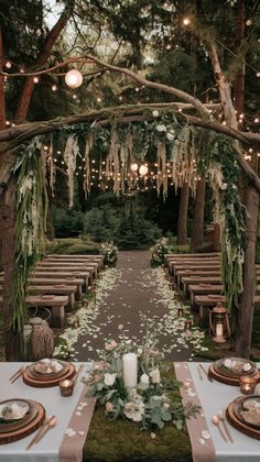 an outdoor wedding setup with white flowers and greenery on the table, surrounded by candles