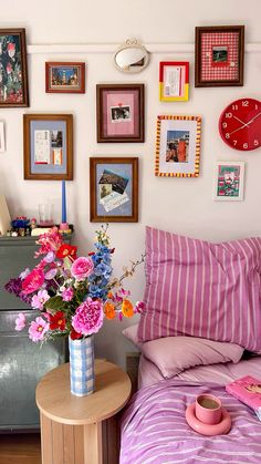 a bedroom with pictures on the wall and flowers in a vase next to a bed