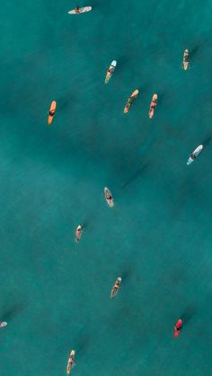 several small boats floating in the water near each other with people on their surfboards