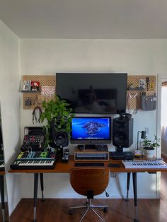 there is a desk with a computer and musical equipment on it in front of a television