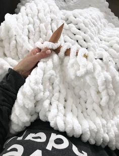 someone is cutting through the yarn on top of a large white blanket that has been made into a sheep