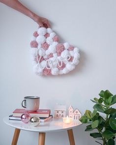 a white table topped with pink and white pom poms next to a potted plant