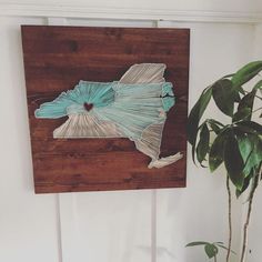 a wooden wall hanging with a piece of paper cut out of the shape of a state