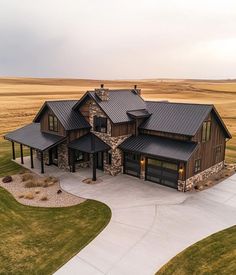 an aerial view of a large house in the middle of a field with grass and dirt