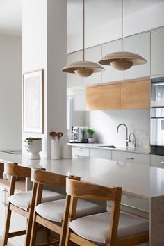 a kitchen with white counter tops and wooden chairs