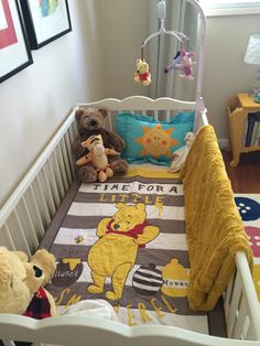 two teddy bears sitting in a crib with winnie the pooh blanket on it