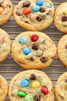 chocolate chip cookies with m & m candy on top are cooling on a rack in the kitchen