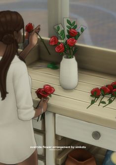 a woman is arranging red roses in a vase