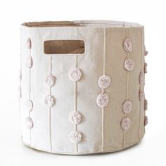 a white and pink storage basket with buttons on the front, hanging from a wooden handle