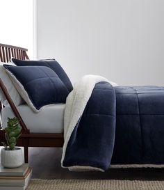 a bed with a blue comforter and white pillows