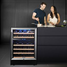 a man and woman standing in front of a wine cooler