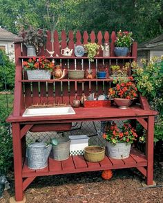 an outdoor kitchen with potted plants and pots on the outside shelf, in front of a fence