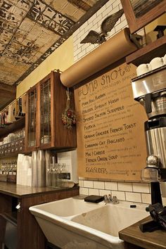 a kitchen with a sink, coffee maker and menu on the wall