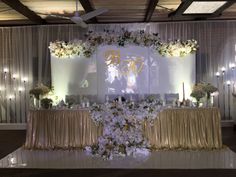 a decorated table with flowers and candles on the top is surrounded by white drapes