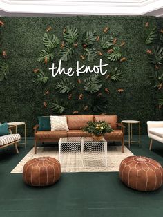 a living room with couches, chairs and plants on the wall that says the knot