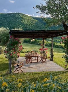 an outdoor table and chairs in the middle of a field with mountains in the background