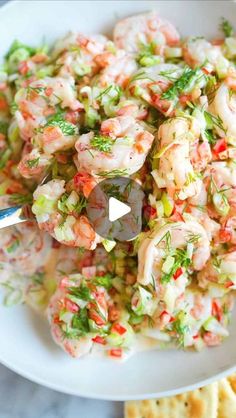 a white bowl filled with shrimp salad next to crackers