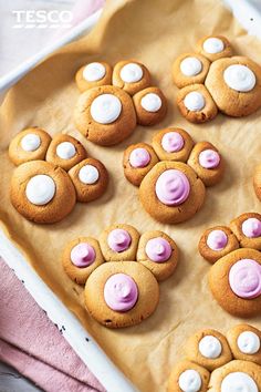 some cookies with pink frosting and white paws on top of them in a pan