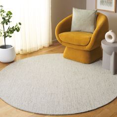 a yellow chair sitting on top of a wooden floor next to a white round rug