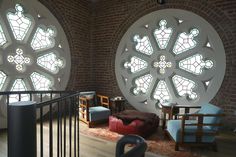 two circular stained glass windows in an old brick building with wooden flooring and furniture