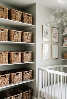 a baby's room with white shelves and baskets on the wall next to a crib